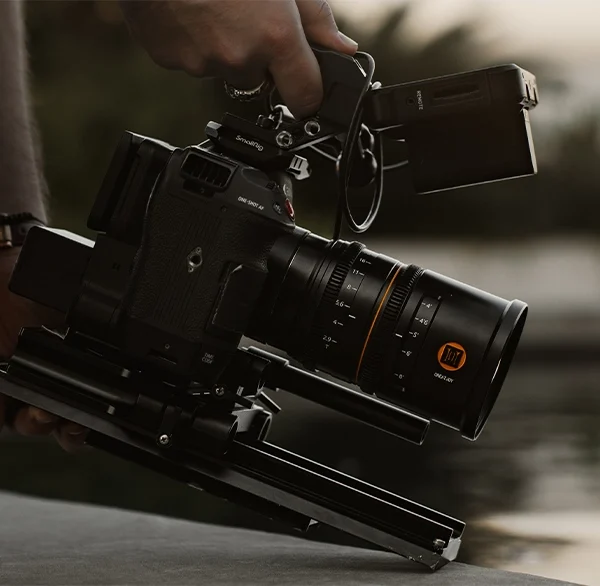 Close-up of a professional cinema camera with a cine lens, mounted on a stabilizer rig during a video shoot.