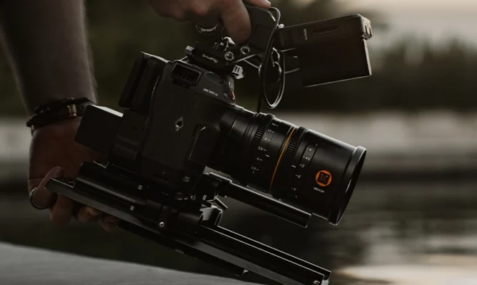 Close-up of a professional cinema camera with a cine lens, mounted on a stabilizer rig during a video shoot.