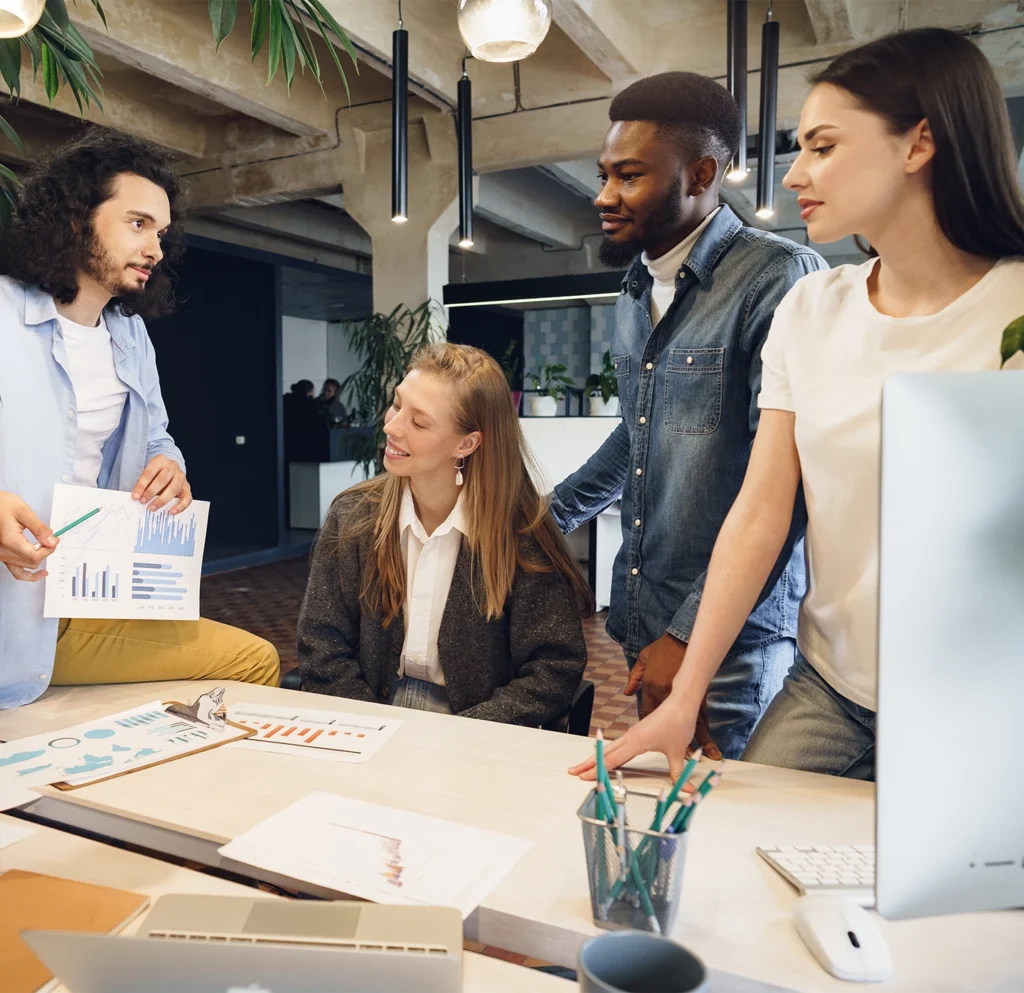 Team of young professionals collaborating in a modern office, reviewing charts and data during a marketing strategy meeting.
